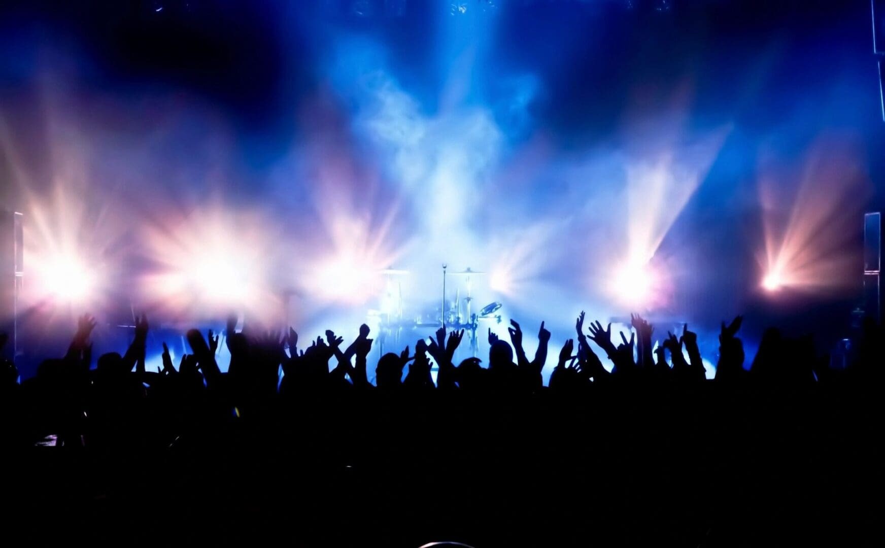 Crowd enjoying a vibrant concert with bright stage lights.