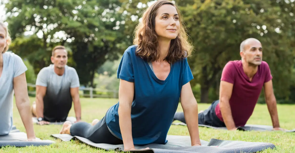 Woman doing yoga stretch outdoors on a mat.